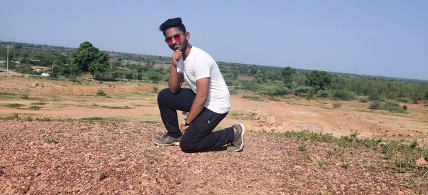 Side view of young man wearing sunglasses on landscape