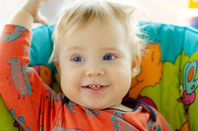 Close-up of thoughtful baby boy smiling while sitting on chair