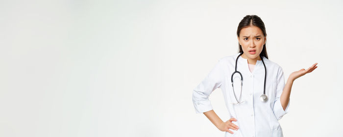 Portrait of doctor standing against white background