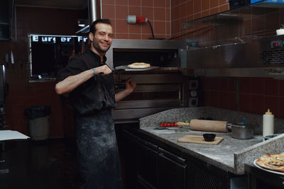 Pizza making process. male chef making authentic pizza in the pizzeria kitchen.