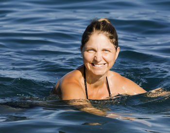 Portrait of smiling young woman swimming in sea