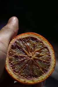 Close-up of hand holding apple against black background