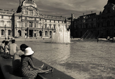 People by fountain against historic building