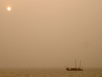 Sailboat sailing on sea against sky during sunset