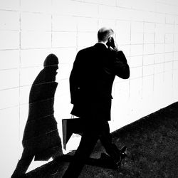 Rear view of a man walking against the wall