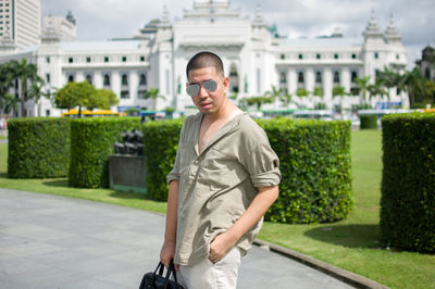 Portrait of young man standing against building in city