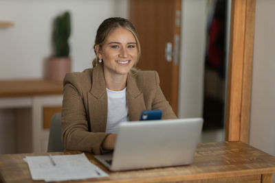 Woman working at home with laptop and speaking on mobile phone. home office. gray notebook 