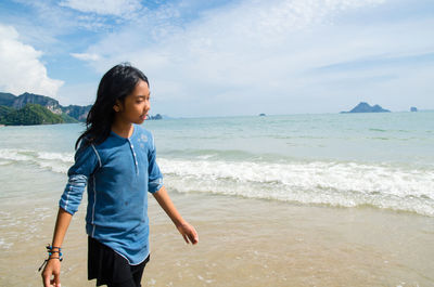 Young woman standing on beach against sky