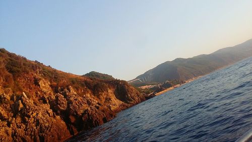 Scenic view of sea and mountains against clear sky