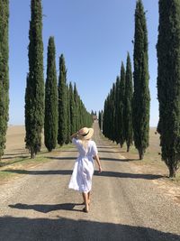 Full length of woman walking by trees against sky