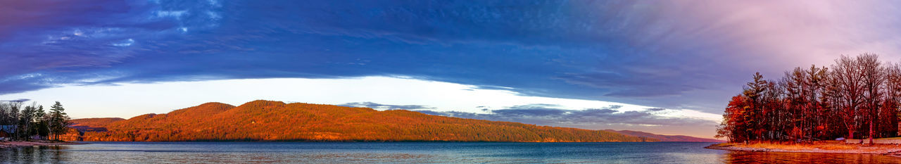 Scenic view of lake by mountains against sky at sunset