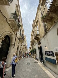 People walking on street amidst buildings in city