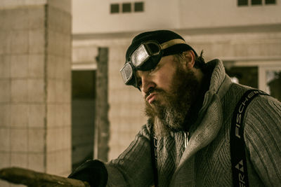 Man wearing aviator glasses while puckering against building