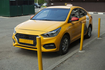 Taxi in the parking lot. a yellow car is parked outside the house. 