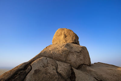 Low angle view of rock formations against clear blue sky