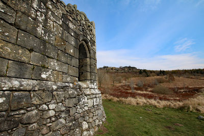 View of old stone wall on field against sky