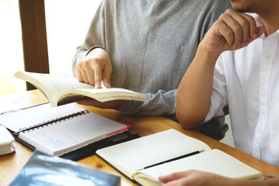 Midsection of man reading book on table