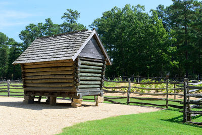 Built structure on field by trees against sky