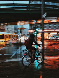 Man riding bicycle on illuminated city at night