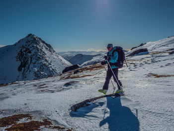 Boy on snowcapped mountain against clear blue sky