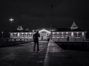 Blur image of silhouette man walking towards illuminated building at night