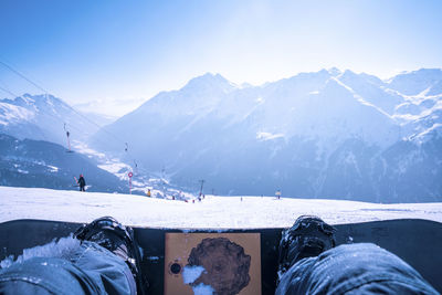 Legs of man snowboarding on snowy mountain landscape