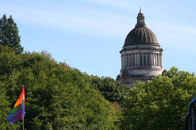 Rainbow flag against trees and state capitol building