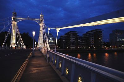 Illuminated bridge over river against sky in city at night