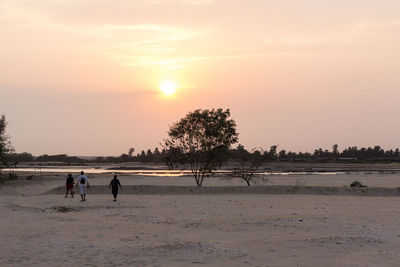 People on beach against sky during sunset