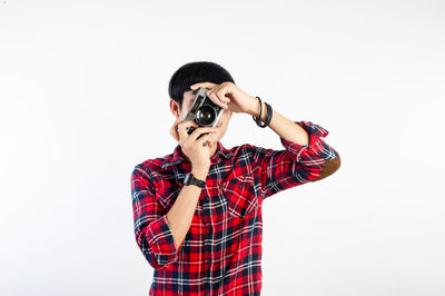 Young woman photographing against white background