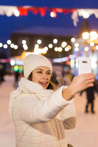 Portrait of smiling man photographing in city during winter