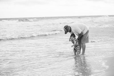 Boy standing on beach against sky