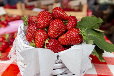 Red ripe fresh strawberry with green leaves in big wooden basket crate on farmers market up