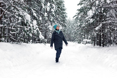 Rear view of man walking on snow covered field