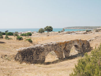 Stone wall on land against clear sky