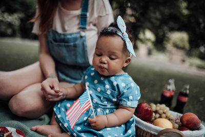 Midsection of mother and daughter sitting outdoors