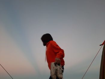 Low angle view of man standing against sky during sunset