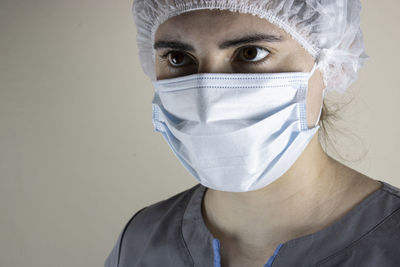 Close-up of doctor wearing mask standing against wall