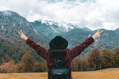 Young woman with outstretched hands, rear view, mountains, adventure.