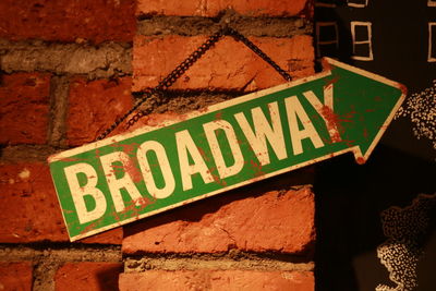 Close-up of sign with broadway text hanging on wall