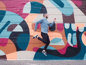 Full length of young woman with graffiti on wall