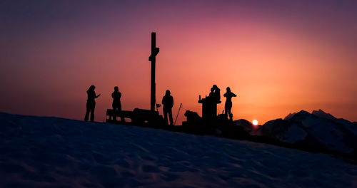 Silhouette people on beach against sky during sunset