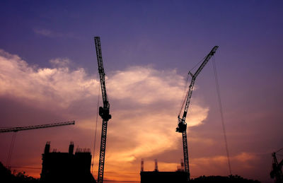 Low angle view of silhouette cranes against sky during sunset