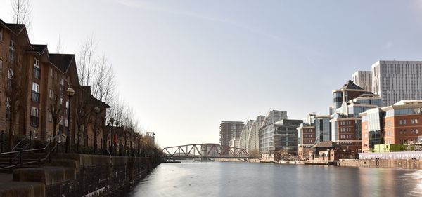 Buildings by river against sky in city