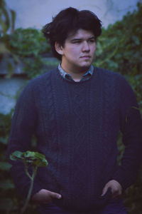 Young man looking away while standing outdoors