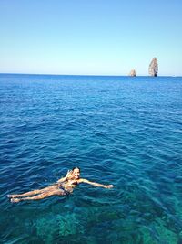 High angle view of woman gesturing while swimming in sea against clear sky