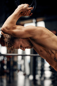 Side view of shirtless man exercising at gym