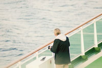 Rear view of man standing on ferry in sea