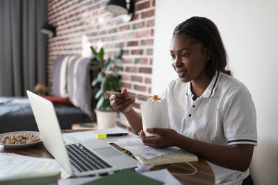 Ethnic student eating chinese food during break