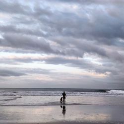 Man with dog on beach against sky